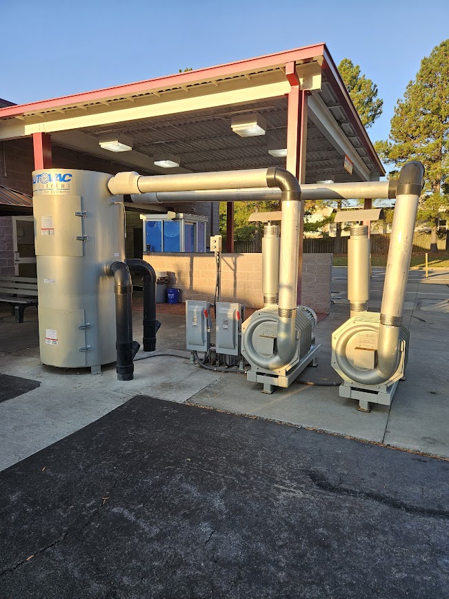 A large commercial pump system with connected pipes and motors, situated under a roof structure in an outdoor setting.